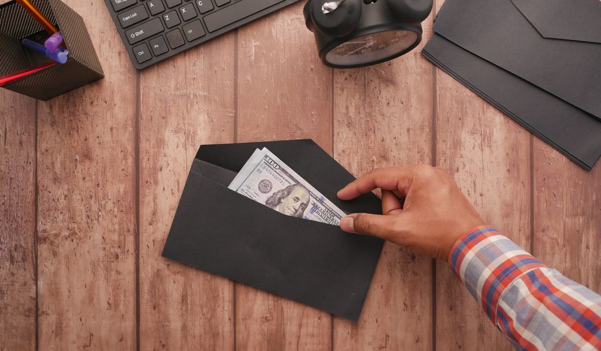 Hombre metiendo dinero en un sobre sobre una mesa de oficina