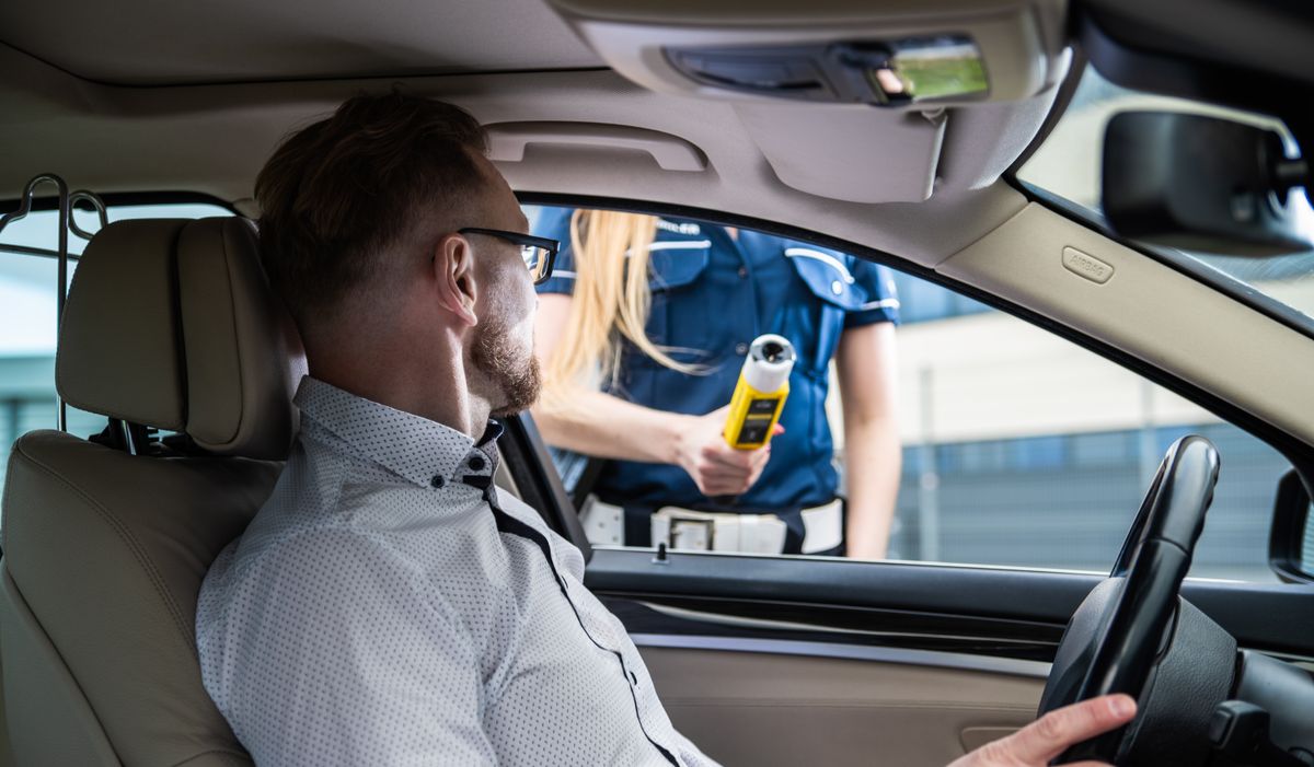 Agente de policía realizando una prueba de alcoholemia con etilómetro a un conductor