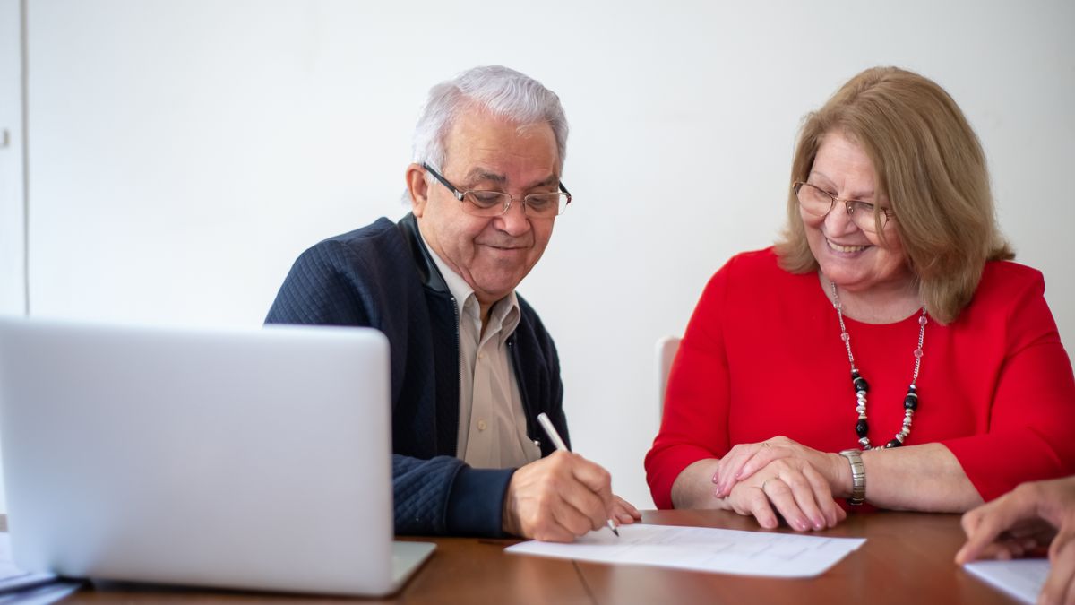 pareja de jubilados firmando un contrato de alquiler en una mesa