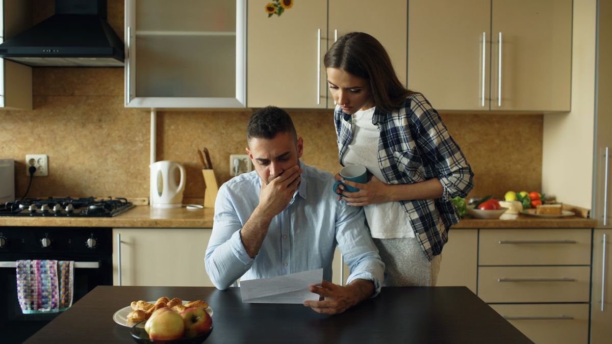 Pareja preocupada leyendo una notificación sobre su vivienda en la cocina de casa