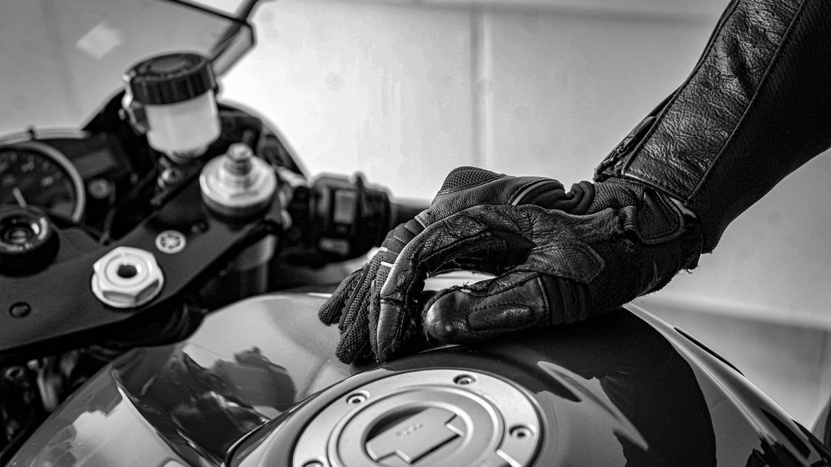 Mano con guante homologado de moto sobre el depósito, el equipo que la DGT obliga desde el 1 de octubre