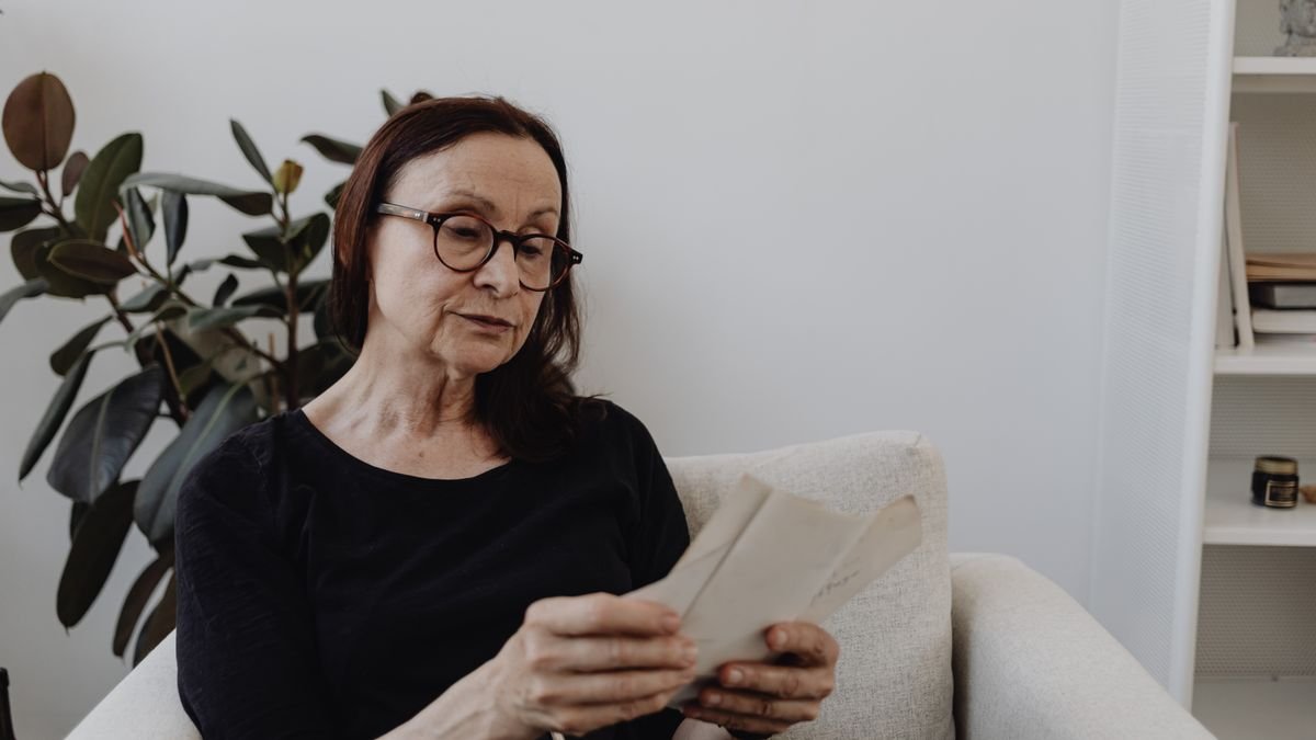 Mujer viuda de mediana edad leyendo con preocupación una carta sobre su pensión de viudedad