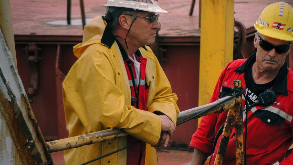 Trabajadores de un astillero con casco y equipo de seguridad en la cubierta de un barco